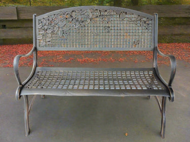 A solid cast iron construction garden bench with a bronze powder coat finish and gold highlights, featuring a grid design and leaves patterns on the backrest.