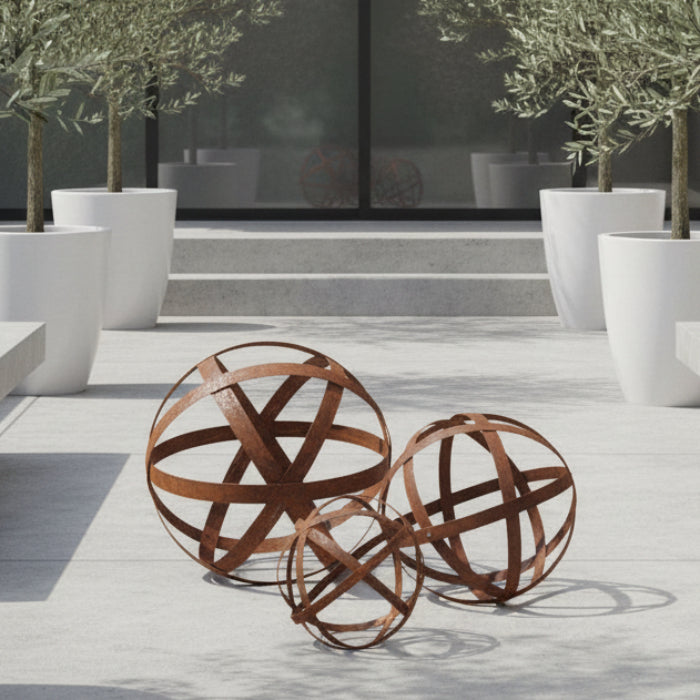 Three rusted metal decorative spheres with intersecting curved bands, shown on a clean white background.