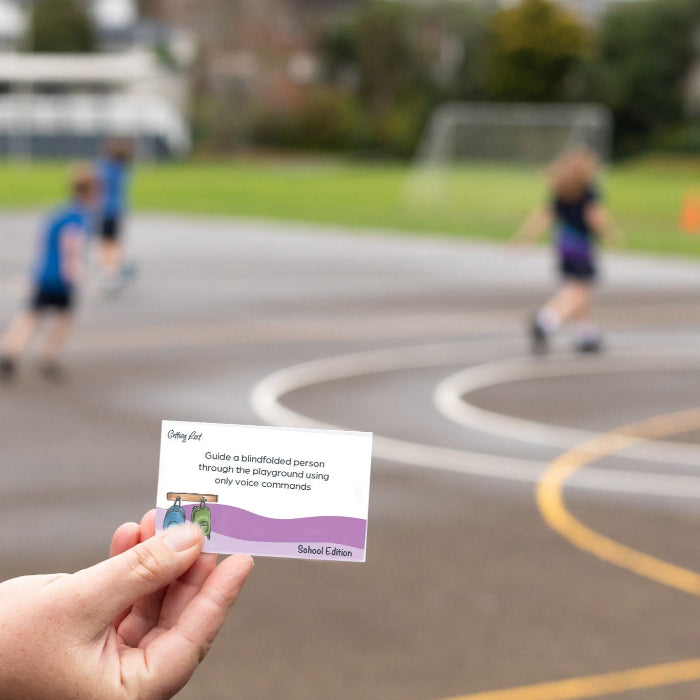 Hand holding a business card with a blurred sports field background