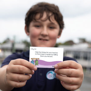 Child holding a card with text outdoors