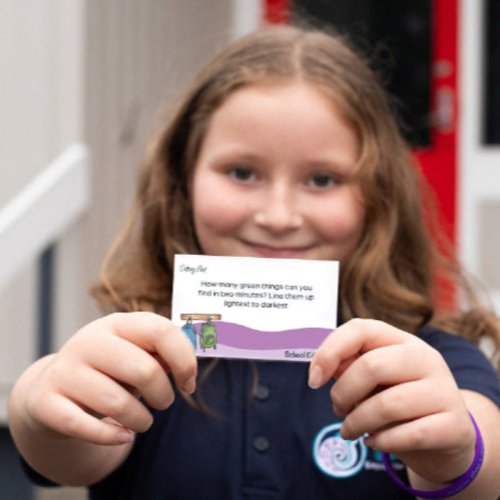 Young girl holding a card with a question on it, standing in front of a fire truck.
