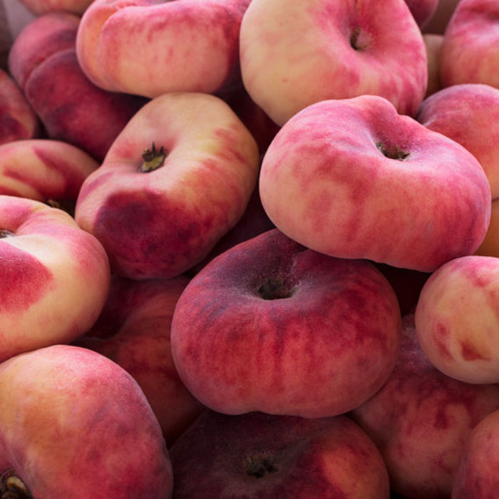 Close-up of a pile of pink and red peaches.