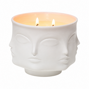 White ceramic face-shaped candle holder with a lit candle inside on a white background