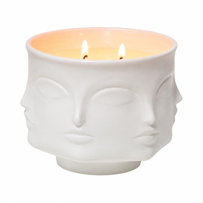 White ceramic face-shaped candle holder with a lit candle inside on a white background