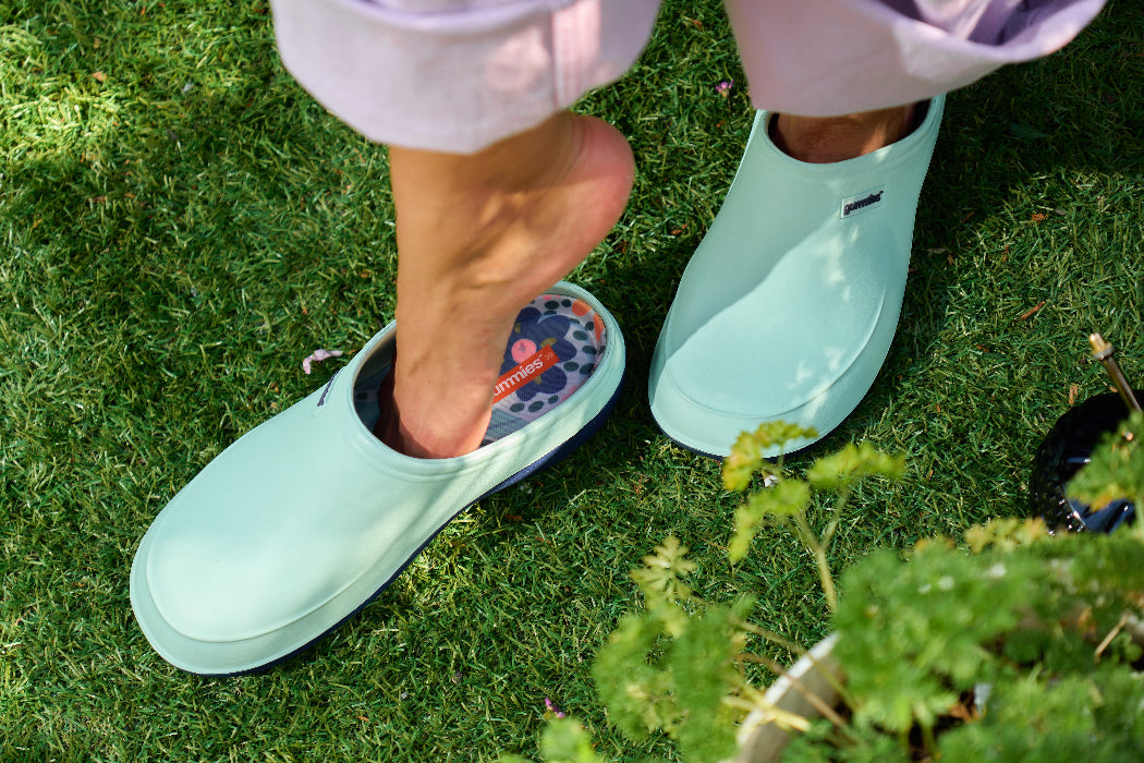 Person wearing light blue garden shoes on grass
