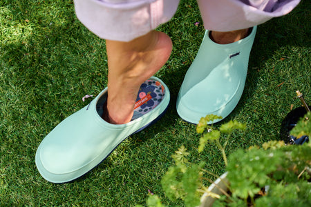 Person wearing light blue garden shoes on grass