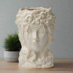 Decorative vase shaped like a woman's face with floral hair on a white background