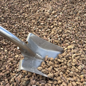 Metal spade partially embedded in a bed of small brown stones