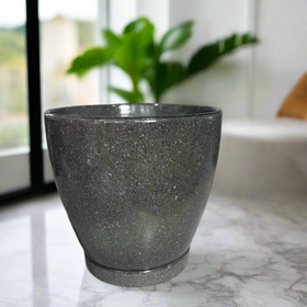 Green textured pot on a concrete surface with decorative items in the background