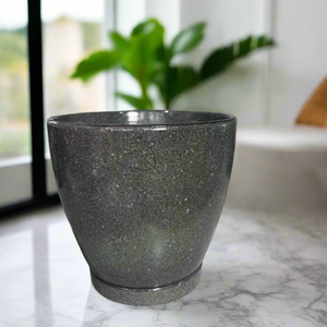 Green textured pot on a concrete surface with decorative items in the background