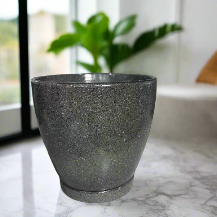 Green textured pot on a concrete surface with decorative items in the background