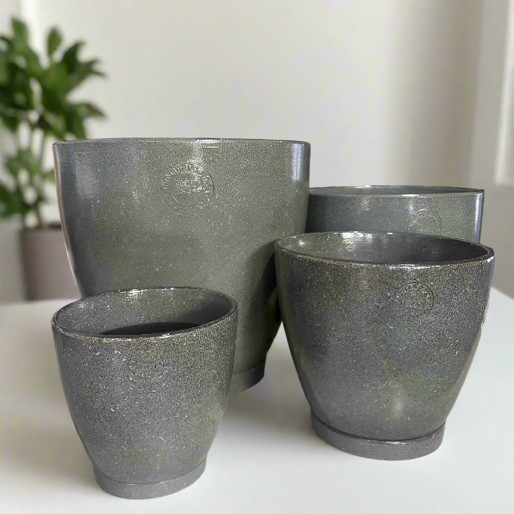 Set of green stone-textured planters on a display table with decorative items in the background.