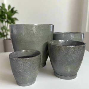 Set of green stone-textured planters on a display table with decorative items in the background.