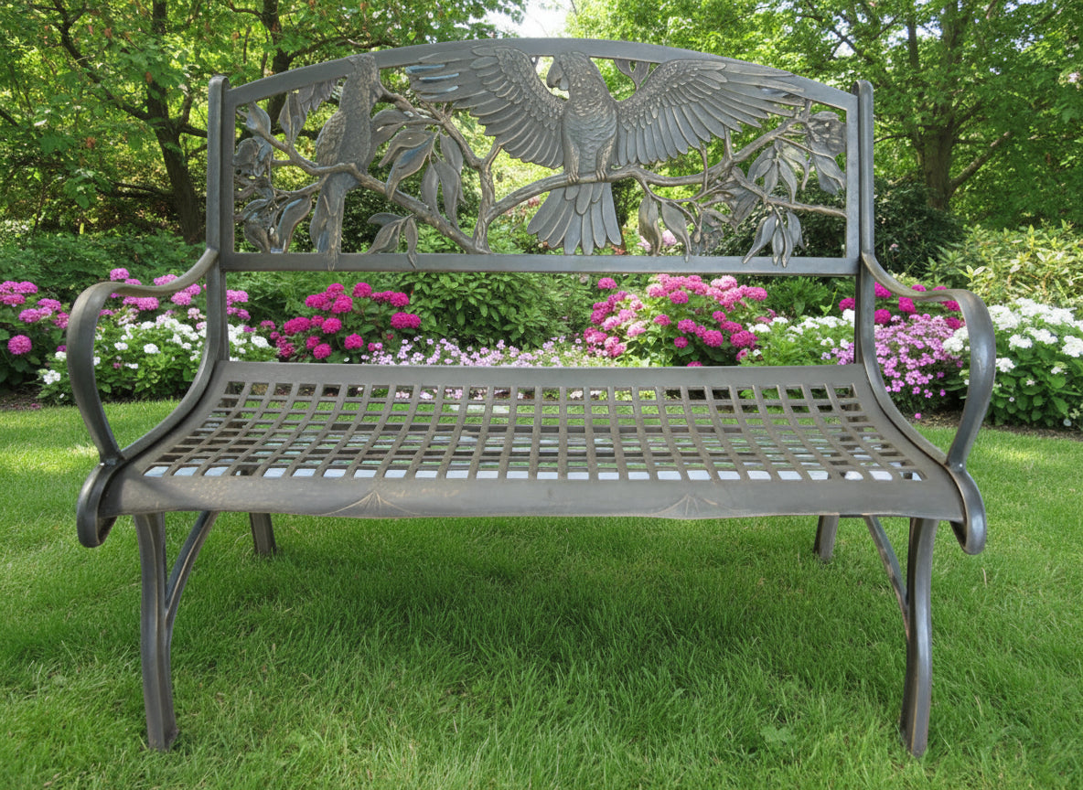 A cast iron outdoor bench with a bronze powder-coat finish and hand painted gold highlights, featuring a bird and foliage design.