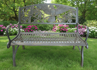 A cast iron outdoor bench with a bronze powder-coat finish and hand painted gold highlights, featuring a bird and foliage design.
