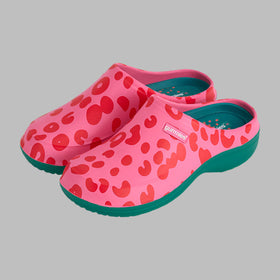 Pink clogs with red heart pattern and green soles on a white background