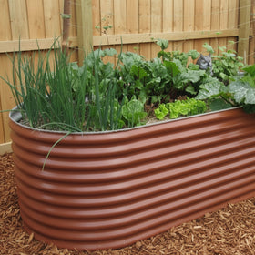 Corrugated metal planter with green plants against a white wall.