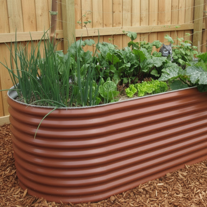 Corrugated metal planter with green plants against a white wall.