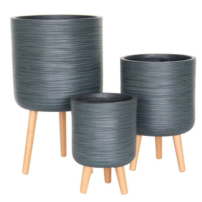 Three cylindrical planters in dark gray with a textured horizontal ribbed pattern and light natural wood legs, shown in a nested size arrangement on a white background.