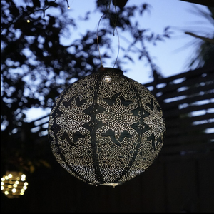 Decorative black lantern with white patterns hanging against a dark background