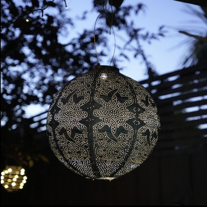 Decorative black lantern with white patterns hanging against a dark background