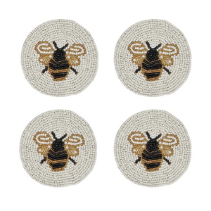 Four round woven coasters featuring a black and gold beaded bumblebee design on a light beige background, arranged in a 2x2 grid on a white background.