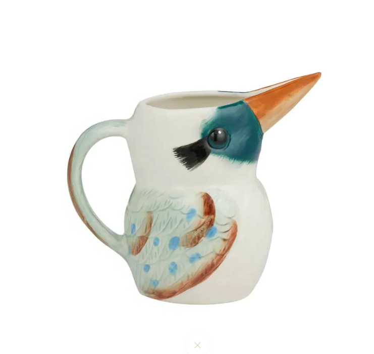 A ceramic pitcher shaped like a kingfisher bird, featuring a white body, a teal and blue head, a long orange beak, and brown and blue feather details on the side, set against a plain white background.