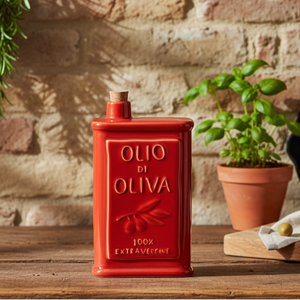 A red ceramic olive oil dispenser bottle with a cork stopper, featuring embossed text that reads 'OLIO DI OLIVA' and '100% EXTRAVERGINE' on a plain white background.