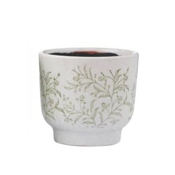 White ceramic cup with green floral patterns on a white background