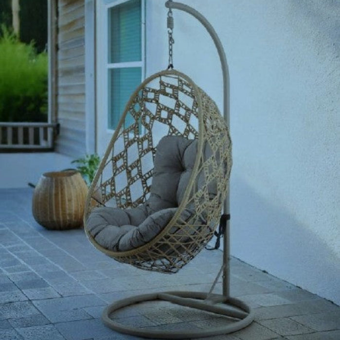 Hanging chair with a cushion on a stand outdoors near a building.