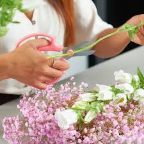 Person arranging flowers with a focus on the bouquet of pink and white flowers.