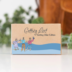 Cardboard box with 'Getting Lost Getting Older Edition' text and illustrations of people on a beach.