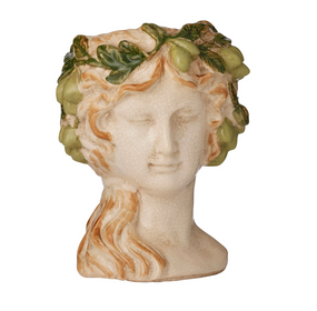 A decorative ceramic bust of a classical female head with closed eyes, styled with wavy tan hair and a green leafy grape crown, isolated on a white background.