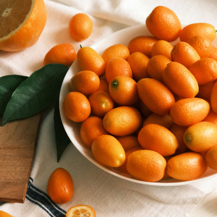 Kumquats in a white bowl on a light fabric background
