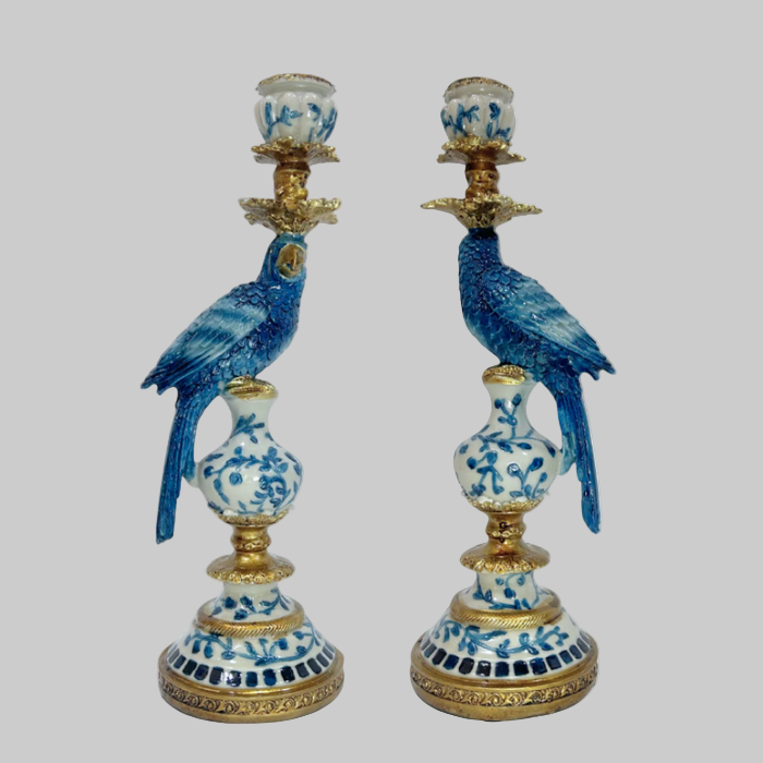 Pair of decorative candle holders with blue parrot designs on a white background