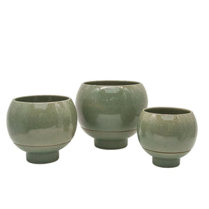 Three green ceramic pots of varying sizes on a white background