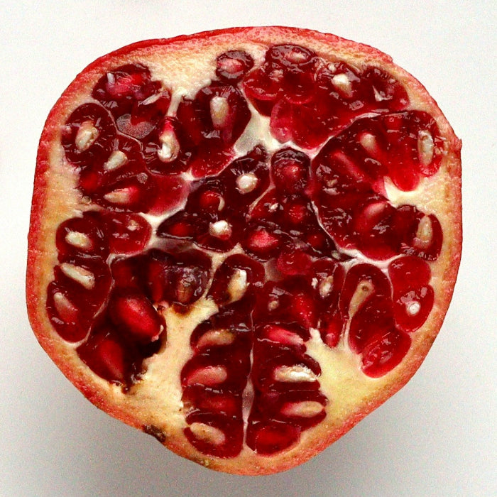Pomegranate cut in half with seeds scattered on a white background