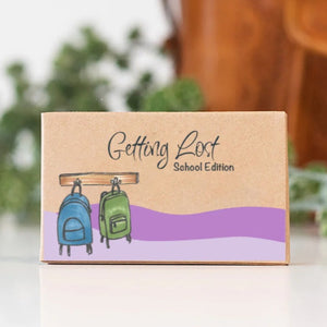 Cardboard box with 'Getting Lost School Edition' text and backpack illustrations on a blurred background