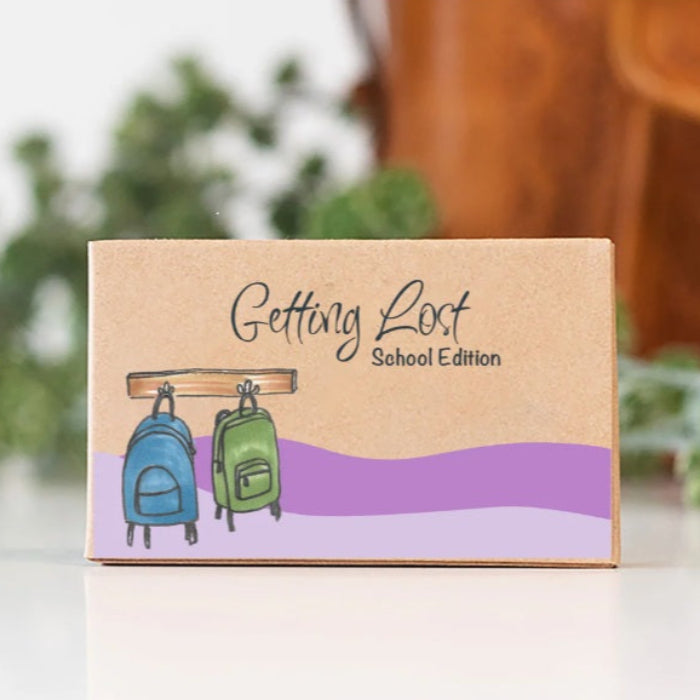 Cardboard box with 'Getting Lost School Edition' text and backpack illustrations on a blurred background