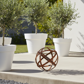 A rustic metal sphere sculpture made of interwoven rusted steel bands, shown on a clean white background.