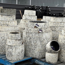 Stack of textured stone planters on a pallet with a blurred background