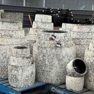 Stack of textured stone planters on a pallet with a blurred background