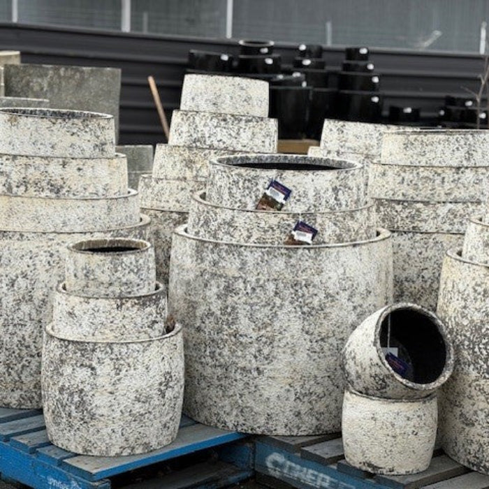 Stack of textured stone planters on a pallet with a blurred background