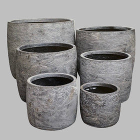 Set of six gray stone planters of different sizes on a light gray background