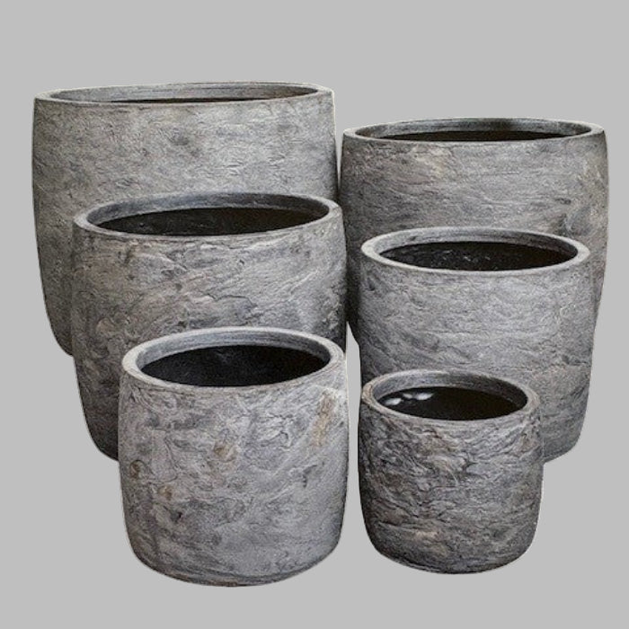Set of six gray stone planters of different sizes on a light gray background
