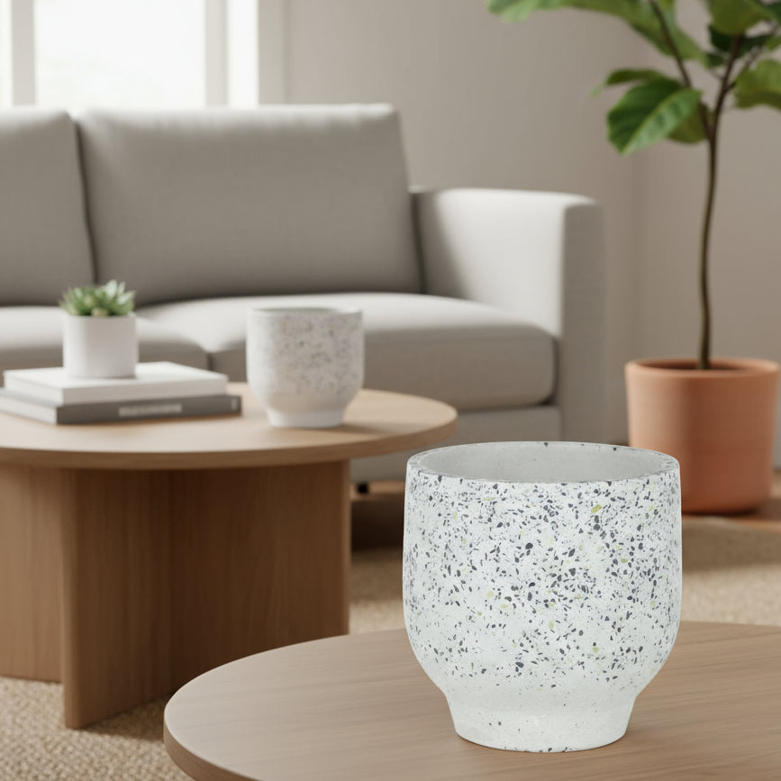 A conical terracotta pot with a white base color and green speckled patterns, featuring a drainage hole.