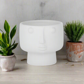 A matte white ceramic pot in the shape of a face, 17cm x 14cm.