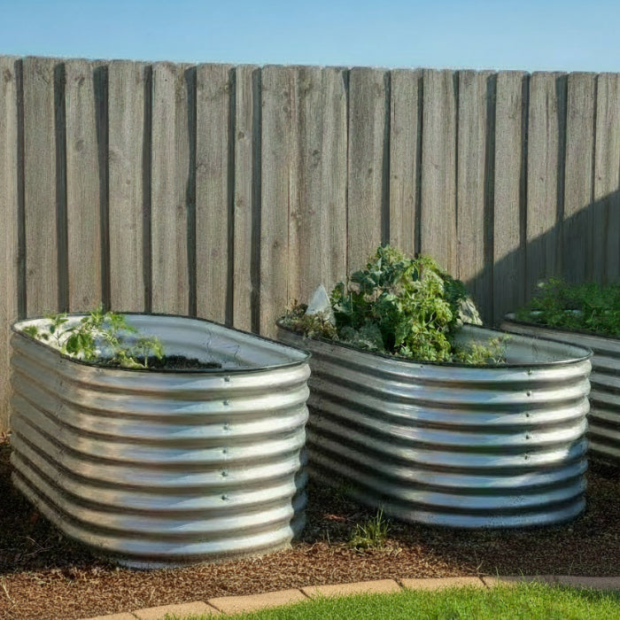 A set of three galvanized metal raised garden beds placed on a garden, with varying sizes, in a outdoor setting.
