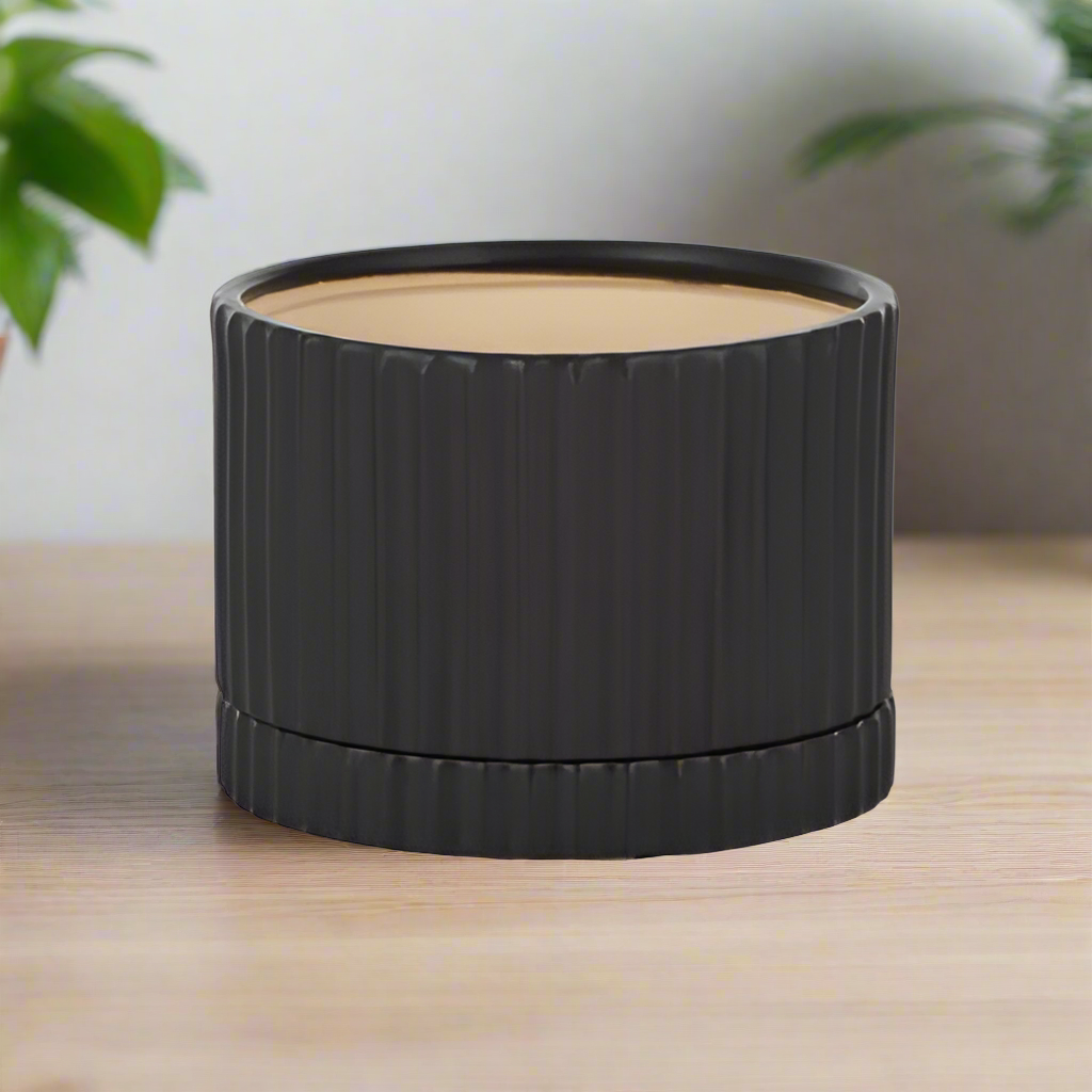 A black ceramic pot with a saucer, suitable for planting, without a drainage hole.